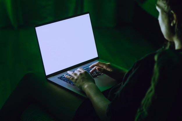 Section médiane d'une femme utilisant un ordinateur portable dans une chambre noire