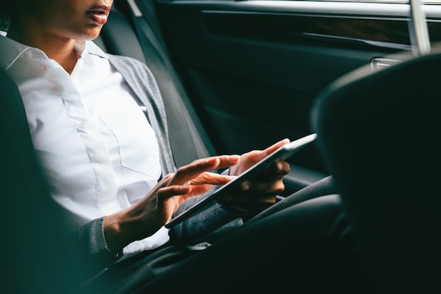 Section médiane d'une femme utilisant une tablette assise dans une voiture