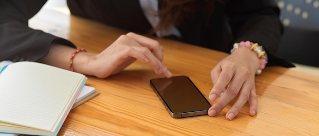 Section médiane d'une femme utilisant un téléphone intelligent sur la table