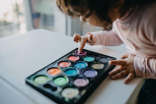 Photo section médiane d'une fille touchant la peinture dans la palette