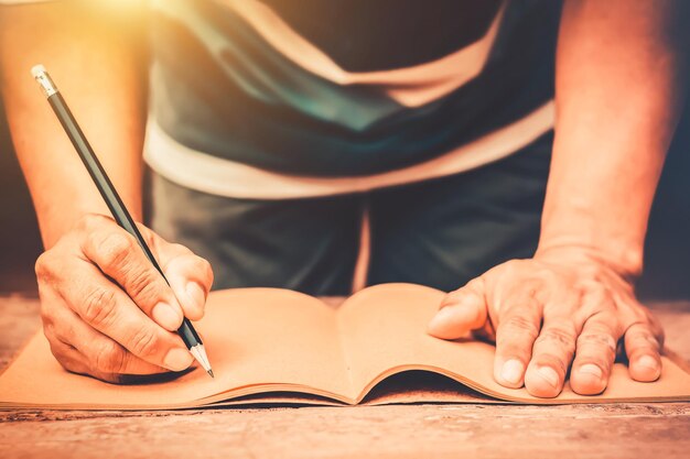 Photo section médiane d'un homme écrivant dans un livre sur une table