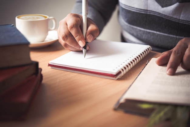 Photo section médiane d'un homme écrivant dans un livre sur une table