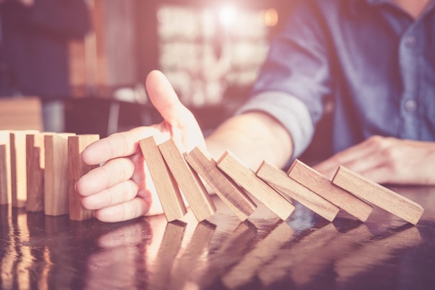 Photo section médiane de l'homme empêchant le domino de tomber sur la table