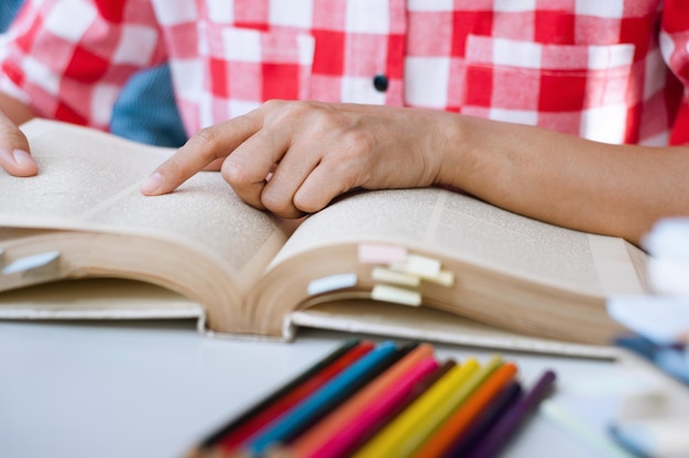 Section médiane d'un homme lisant un livre sur une table de la bibliothèque