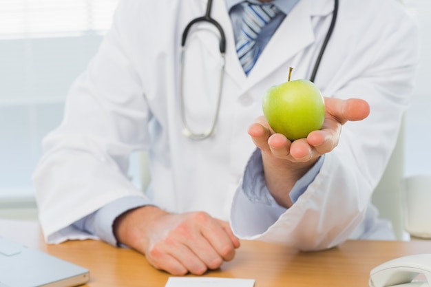 Section médiane d&#39;un homme médecin tenant une pomme