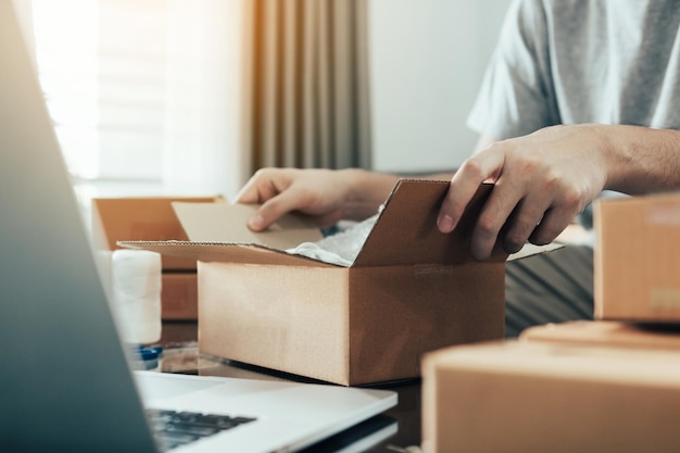 Section médiane d'un homme ouvrant une boîte en carton sur la table à la maison