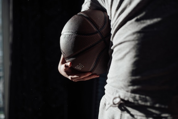 Section médiane de l'homme tenant la balle alors qu'il se tient contre un fond noir