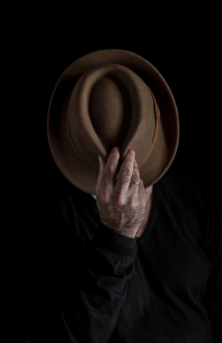 Photo section médiane d'un homme tenant un chapeau sur un fond noir