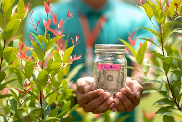 Photo section médiane d'un homme tenant de la monnaie dans un pot avec un texte éducatif par des plantes