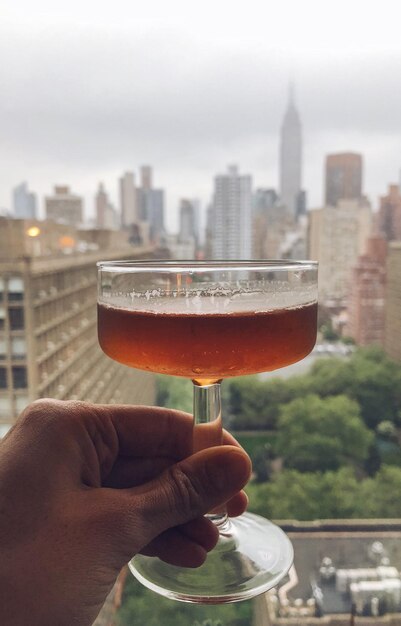 Photo section médiane d'un homme tenant un verre contre des bâtiments en ville