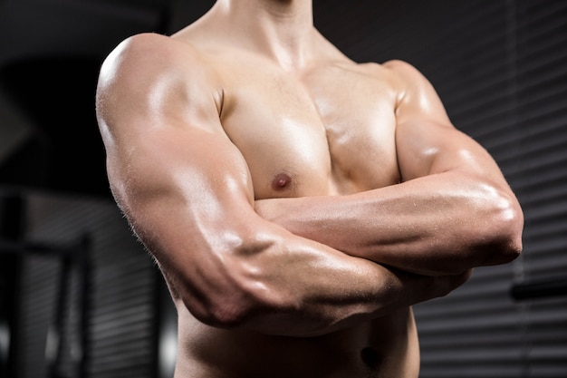 Photo section médiane d'un homme torse nu aux bras croisés dans le gymnase de crossfit