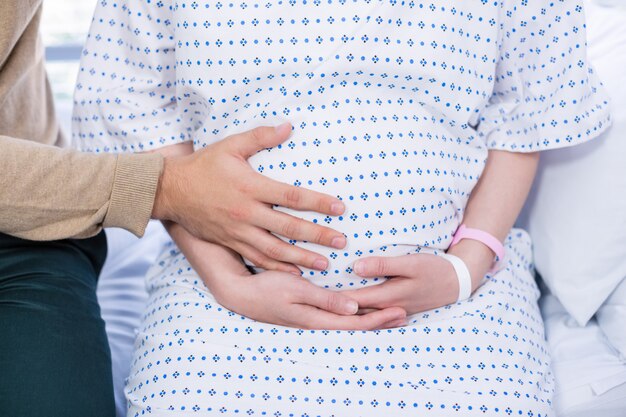 Section médiane de l'homme touchant le ventre de femme enceinte dans la salle