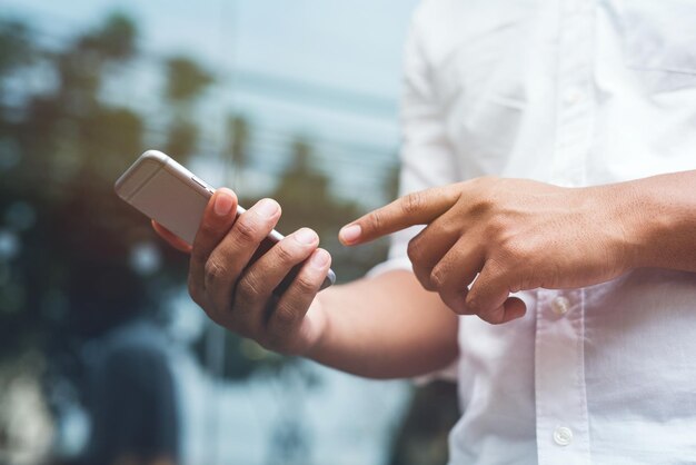 Photo section médiane d'un homme utilisant un téléphone alors qu'il se tient à l'extérieur