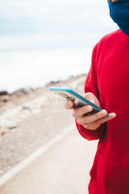 Section médiane d'un homme utilisant un téléphone portable contre la mer