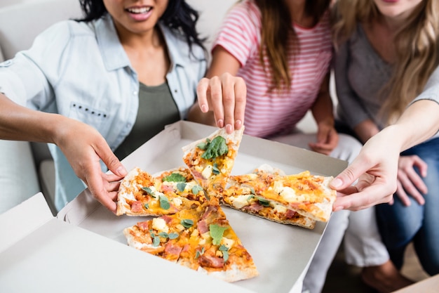 Section médiane de jeunes amies en train de manger une pizza