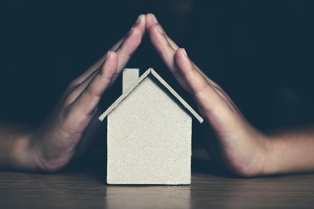 Photo section médiane des mains d'une personne par modèle de maison sur table