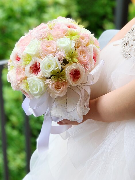 Photo section médiane de la mariée tenant un bouquet à l'extérieur