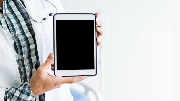 Section médiane d'un médecin tenant une tablette numérique sur fond blanc