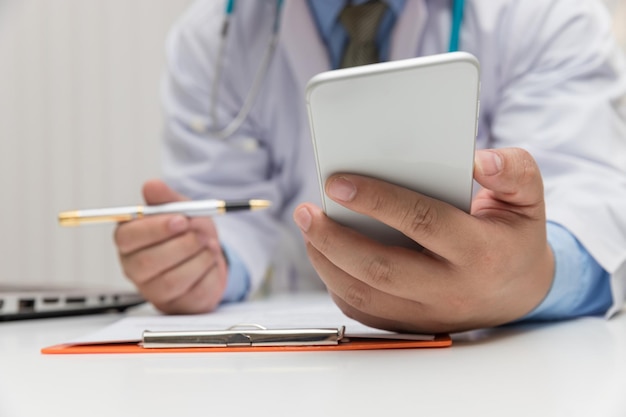 Photo section médiane d'un médecin utilisant le téléphone à son bureau à l'hôpital