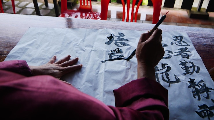 Photo section médiane d'une personne écrivant avec un pinceau sur papier