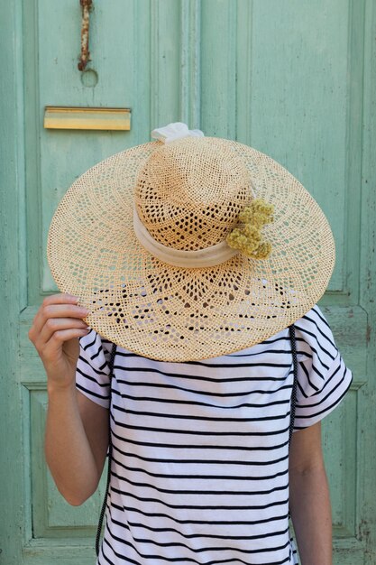 Photo section médiane d'une personne portant un chapeau contre le mur