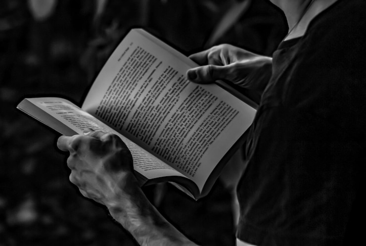 Photo section médiane d'une personne tenant un livre dans une chambre noire