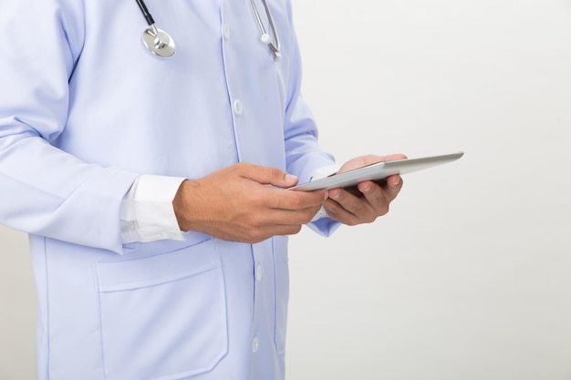 Section médiane d'une personne tenant une tablette numérique debout sur un fond blanc