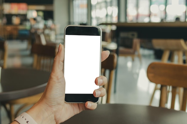 Section médiane d'une personne tenant un téléphone portable dans un café