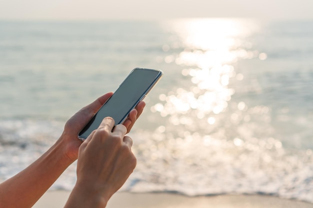 Section médiane d'une personne utilisant un téléphone portable contre la mer