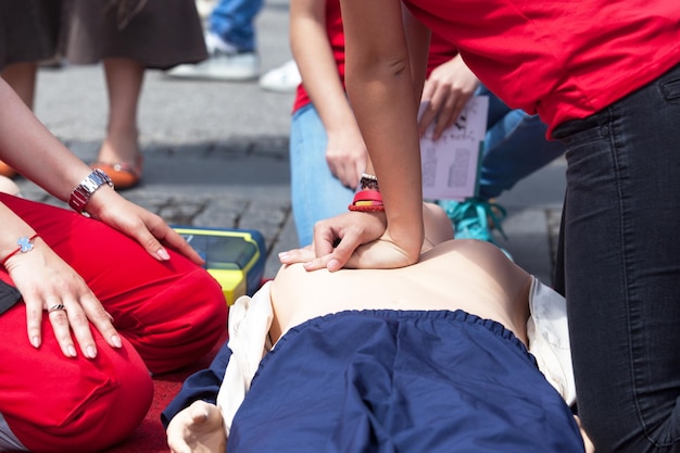 Photo section médiane de personnes avec un mannequin de réanimation cardiaque pendant l'entraînement