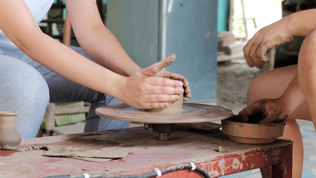 Photo section médiane de personnes travaillant sur une roue de poterie à l'atelier