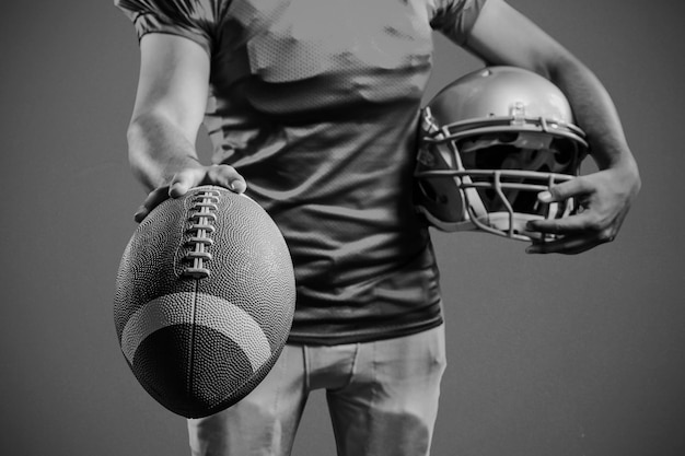 Photo section médiane d'un sportif montrant le football américain tout en tenant un casque sur fond bleu