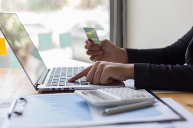 Section moyenne d'une femme d'affaires tenant une carte de crédit et utilisant un ordinateur portable au bureau