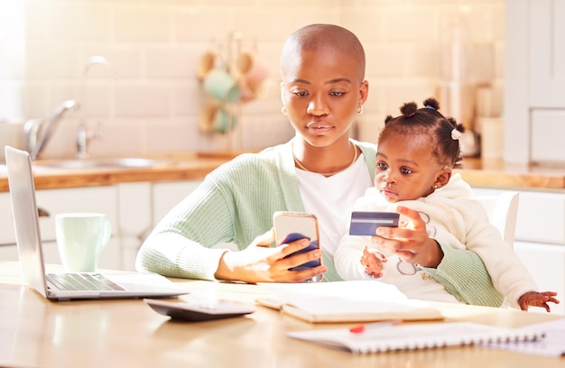 Sécuriser notre avenir un paiement à la fois. Photo d'une jeune femme effectuant des paiements par carte tout en tenant son bébé et en travaillant à domicile.