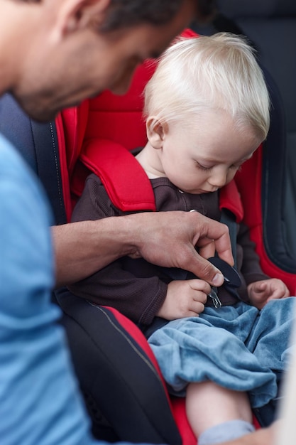 La sécurité d'abord Un père aidant son enfant dans un siège bébé pour la voiture