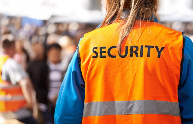 Photo la sécurité est l'objectif principal vue arrière d'un agent de sécurité debout à l'extérieur avec une foule en arrière-plan