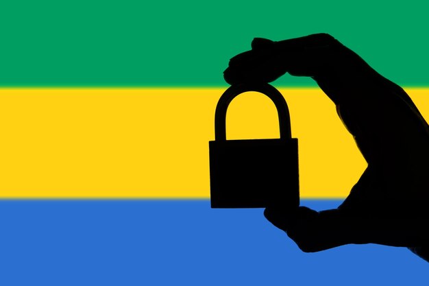 Sécurité Gabon Silhouette de main tenant un cadenas sur le drapeau national