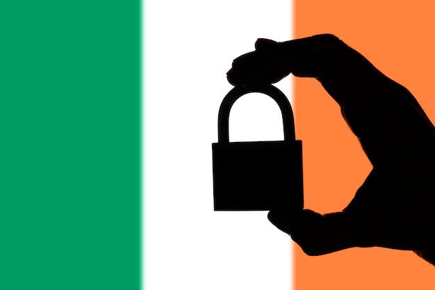 Sécurité de l'Irlande Silhouette de main tenant un cadenas sur le drapeau national