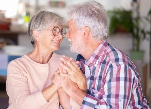 Séduisant couple de personnes âgées joyeux et souriant s'embrassant à la maison se regardant dans les yeux Relation forte pour deux personnes âgées de race blanche s'amusant ensemble