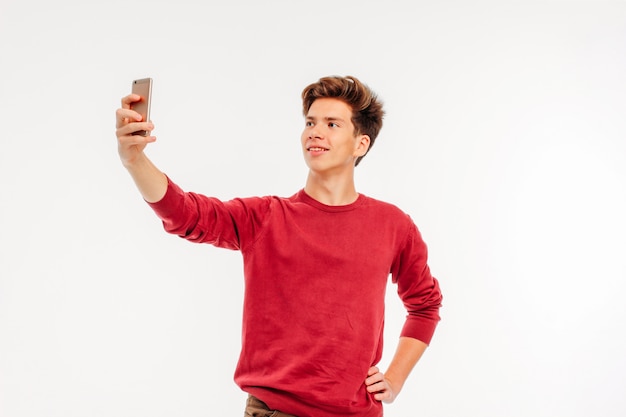 Photo séduisant jeune homme adolescent fait un selfie avec smartphone sur