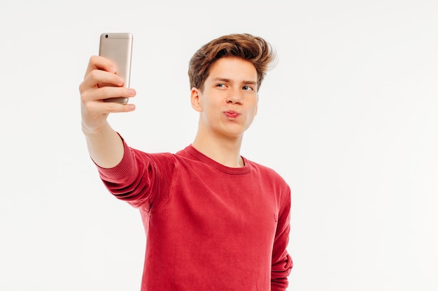 Photo séduisant jeune homme adolescent fait un selfie avec smartphone sur