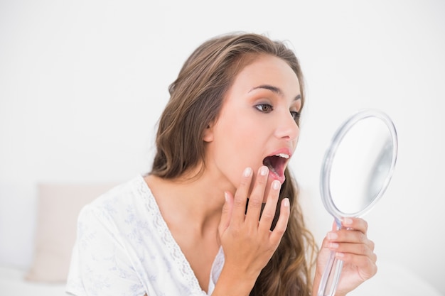 Séduisante brune en ouvrant la bouche et en regardant le miroir