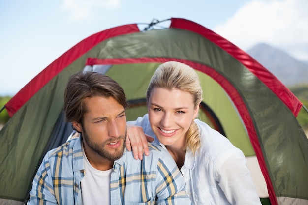 Photo séduisante couple heureux assis près de leur tente, souriant à la caméra