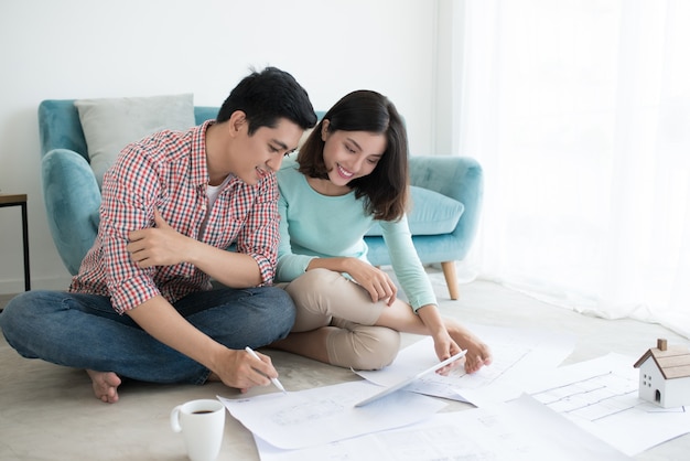 Séduisante jeune couple adulte asiatique regardant les plans de la maison.