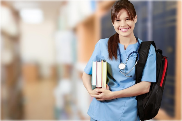 Séduisante jeune étudiante en médecine avec sac à dos et livres sur fond de bibliothèque