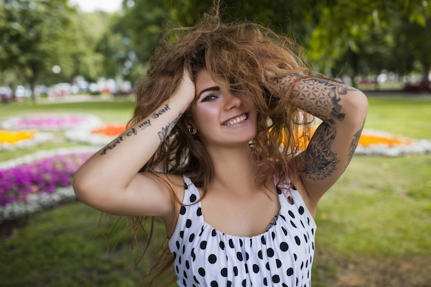 séduisante jeune femme aux cheveux sauvages bouclés et aux tatouages.