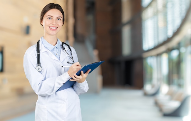 Séduisante jeune femme médecin avec intérieur flou de l'hôpital