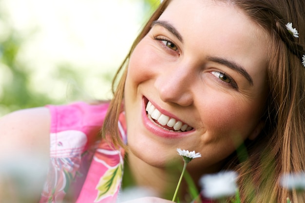 Séduisante jeune femme souriante avec fleur à l&#39;extérieur