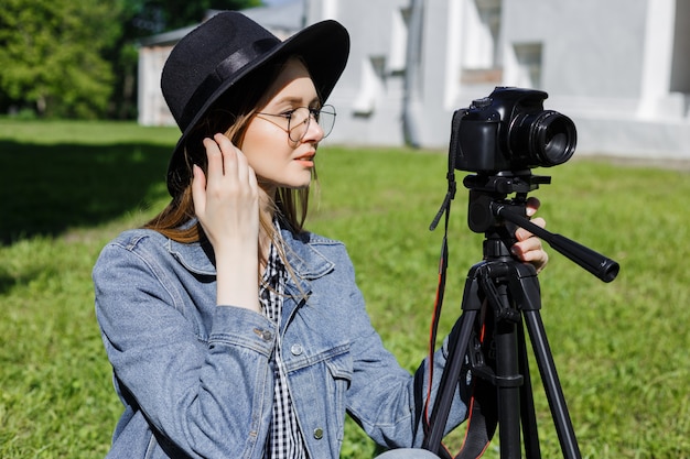 Séduisante jeune fille au chapeau fait une photo sur l&#39;appareil photo à l&#39;extérieur