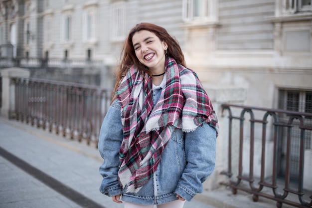 Séduisante jeune fille en veste en jean et rire dans la rue.